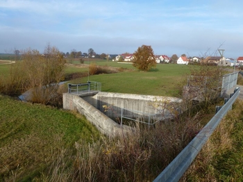 Ansicht vom Erddamm in Beckeneinstauraum mit Hochwasserentlastungsschwelle bei leerem Becken